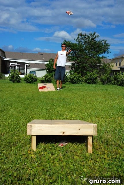 A person testing out the newly built cornhole game, tossing a bean bag