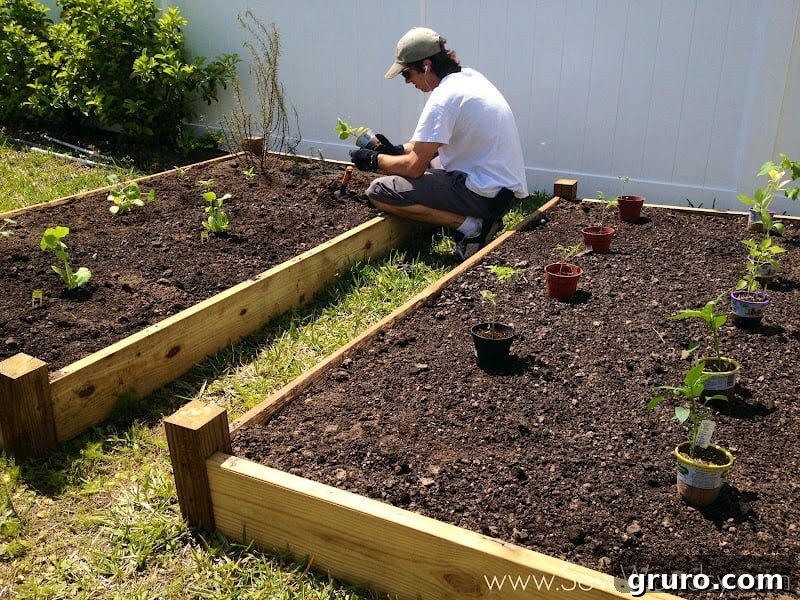 Mr. Woodsy meticulously filling a raised garden bed with fresh, nutrient-rich soil, preparing it for planting.