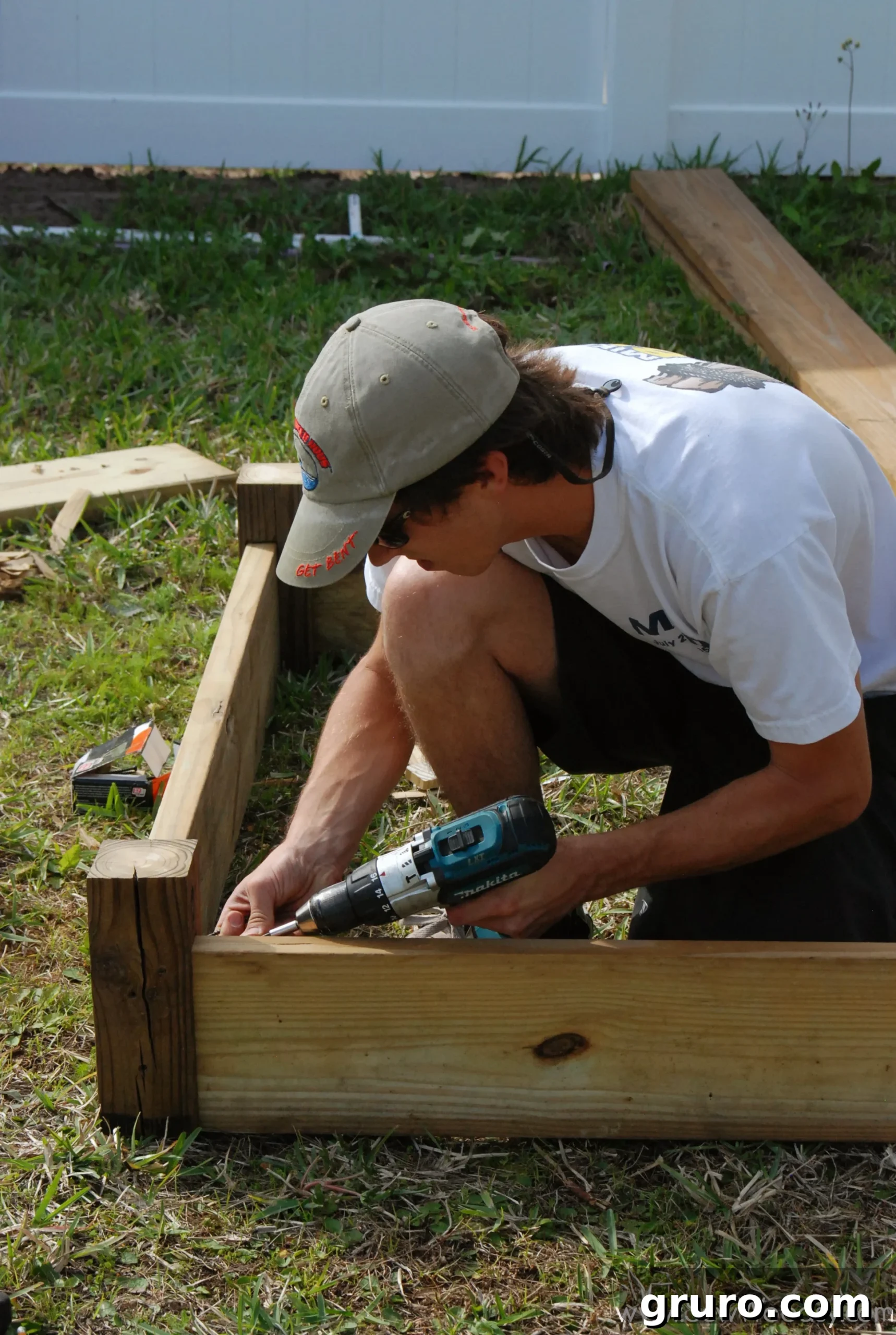 Close-up view of a partially assembled raised garden bed corner post, showing drilled holes and secured lumber.