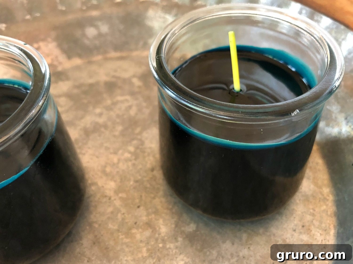 Pouring dark blue colored wax into Oui yogurt jars to create homemade candles