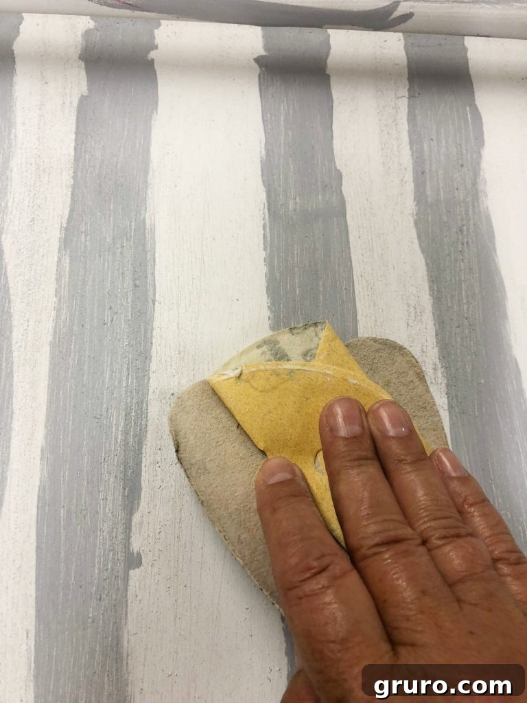 Lightly sanding the painted thrift store tray to create a distressed effect.