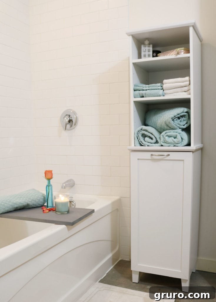 Tall storage unit with a built-in hamper, ideal for organized bathroom storage solutions.