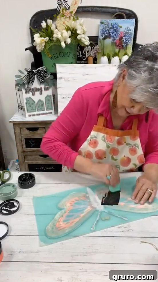 Applying black chalk paste over the butterfly stencil