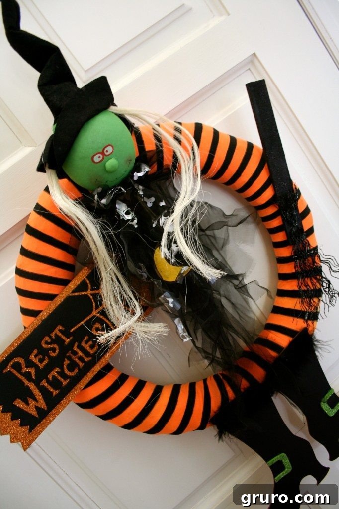 Close-up of the Halloween wreath showcasing a green-faced witch figure with mesmerizing, seemingly watchful eyes that follow you