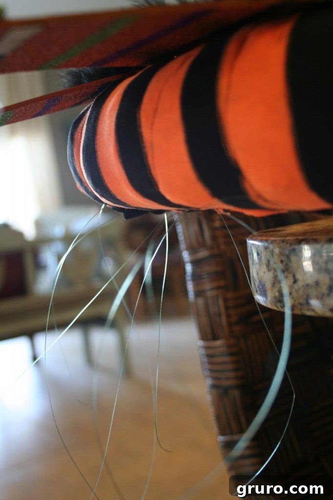 Close-up showing how fishing line is discreetly tied around a Halloween decoration and secured to the wreath, creating a seamless attachment