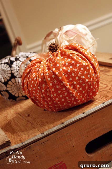 Orange cloth pumpkin on a wood crate, decorated for fall.