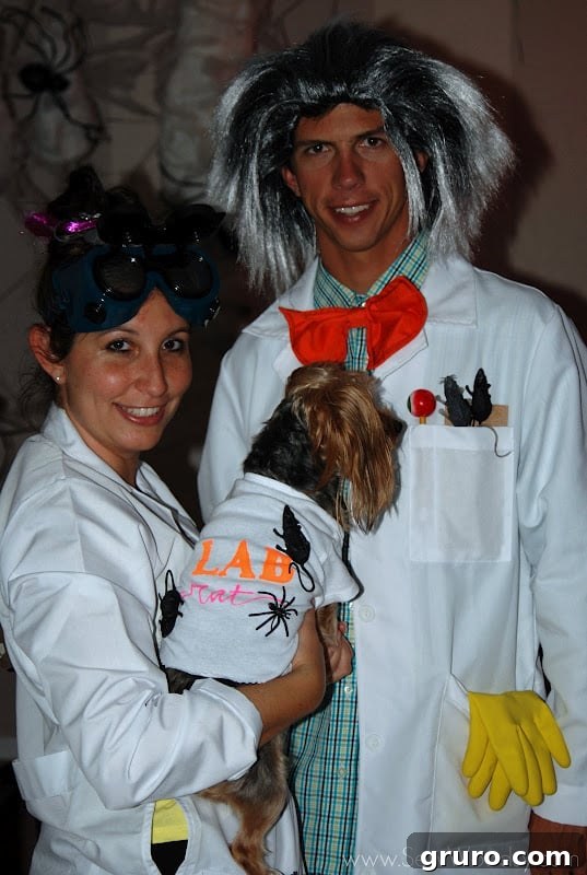 A man and woman in lab coats holding a dog, dressed as quirky scientists for a Halloween costume.