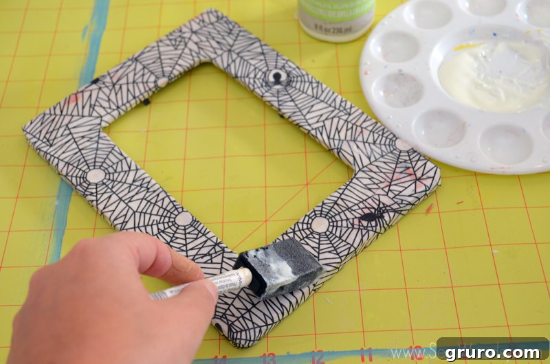Cutting slits into the center of the decoupage paper to form flaps for the inner frame opening, then gluing and trimming for a neat finish.
