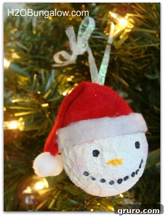 A snowman ornament featuring a red felt hat with white trim and a pom-pom, showcasing handmade charm.