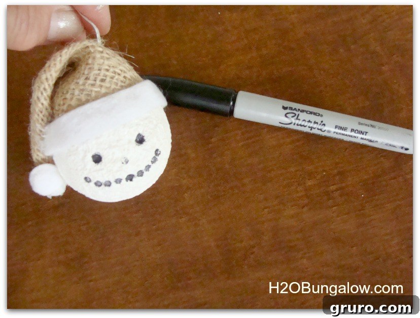 Close-up image of a snowman ornament's face, showing drawn eyes and mouth with a Sharpie.