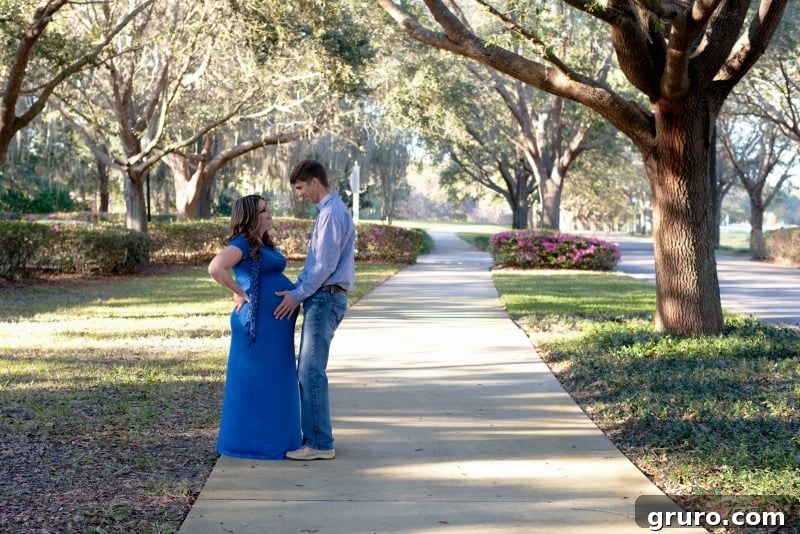 Joyful maternity photo of expectant parents in a lush park setting