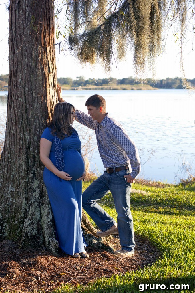 Expectant mother leaning against a tree, peaceful outdoor maternity photo