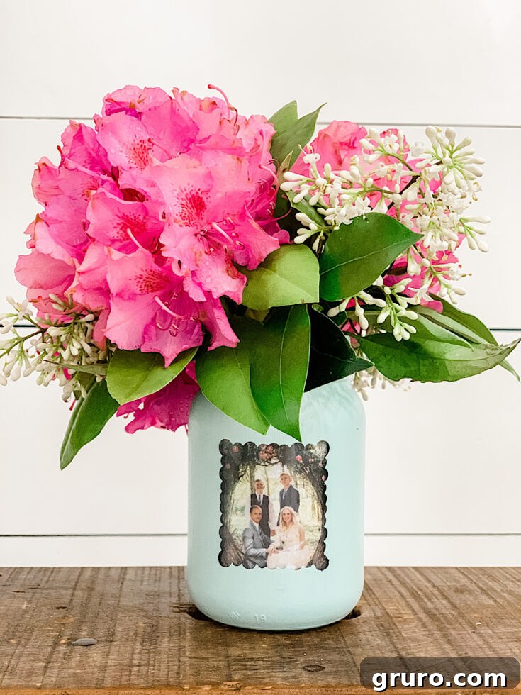 A creative mason jar vase with a small picture frame attached, perfect for displaying flowers and a cherished photo simultaneously, an excellent Mother's Day gift.