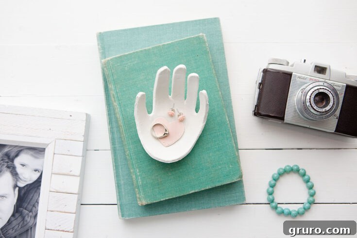 A beautifully crafted clay jewelry dish with a child's handprint embossed on it, painted and finished for a personalized touch, perfect for Mother's Day.