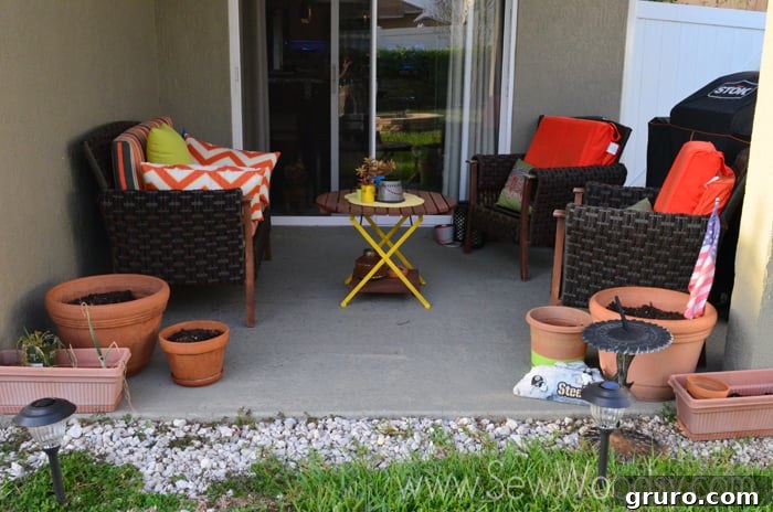 Our old, unpainted concrete patio featuring two chairs, a couch, and empty pots, before its transformation.