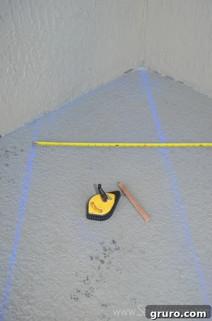 Measuring tape laid on a patio floor with chalk lines already marked for a geometric design.