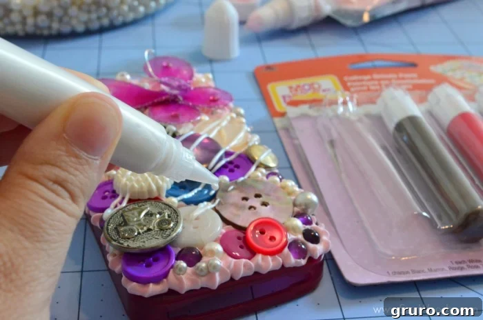 A fully decorated Decoden phone case, showcasing a vibrant composition of buttons, pearls, and purple gems, topped with a striking 3D butterfly. This image highlights the case's appearance before the application of Collage Drizzle Paint, offering a clear view of the intricate details and layered textures.