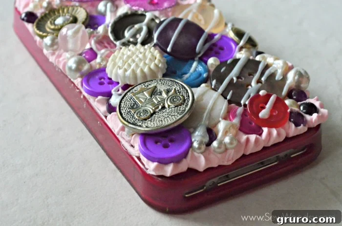 A close-up side view of the completed Decoden phone case, showing the carefully flattened edges of the Mod Podge Collage Clay. The intricate 3D embellishments, including buttons, pearls, and a butterfly, are perfectly set, demonstrating a polished finish and attention to detail. #plaidcrafts #modpodge