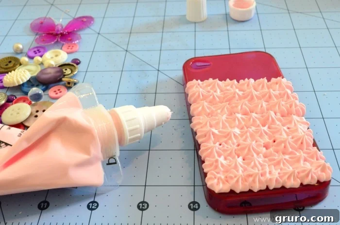 A close-up view of a cell phone case with a substantial layer of Strawberry Pink Mod Podge Collage Clay being meticulously applied, ensuring no visible gaps remain. The crafter's attention to detail is evident as the whipped clay is evenly spread across the case, forming a smooth and continuous base for subsequent embellishments.