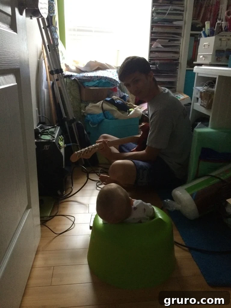 Daddy Jon playing guitar and singing to baby Ryder in the craft room