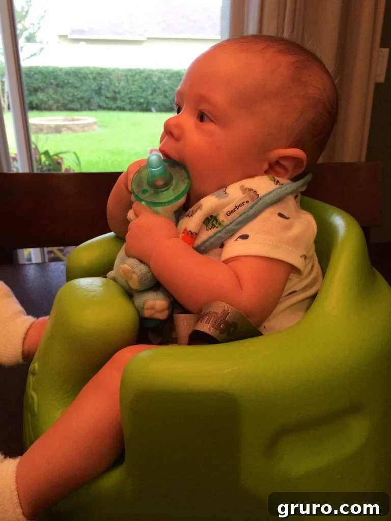 Baby Ryder sitting upright in his Bumbo chair for the first time, exploring his surroundings