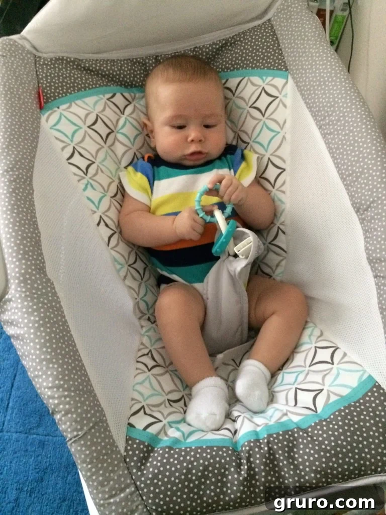 Mom working while baby Ryder relaxes in his rock and play chair, balancing parenting and work