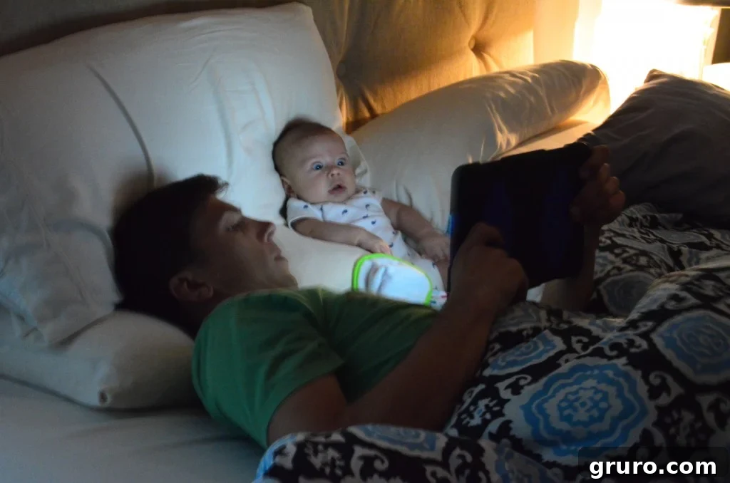 Baby Ryder engaged with content on an iPad while daddy looks on, showcasing modern baby interaction