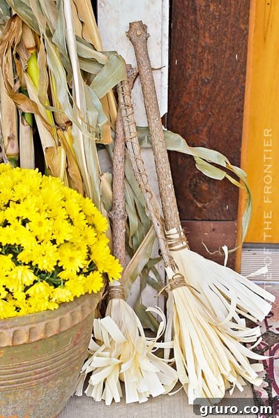 A trio of handmade corn husk brooms, leaning against a wall, adding a rustic fall and witchy touch.