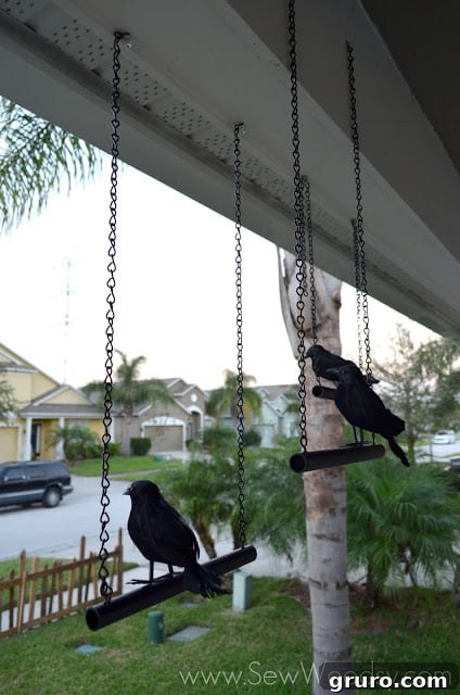 Several fake crows perched on a fence, observing, creating a subtle yet eerie Halloween atmosphere.