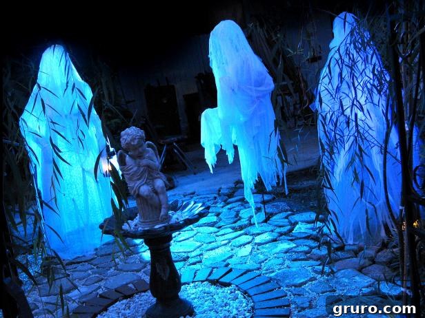 A human-sized ghost figure made from chicken wire and sheer fabric, standing in a yard at night.