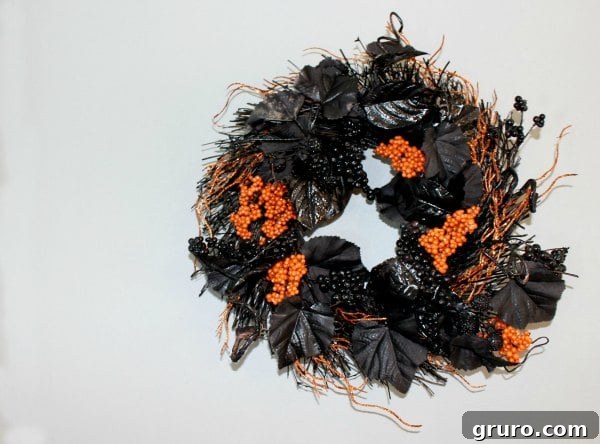 A black and orange Halloween wreath with spiderwebs and a spider, made for under $10.