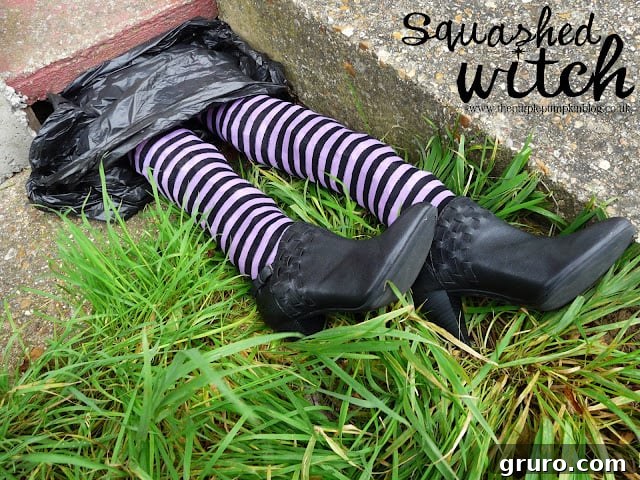 A pair of striped witch legs and red shoes sticking out from under an object, resembling a squashed witch.