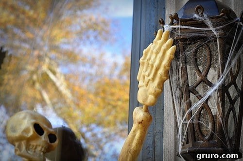 Plastic skeletons climbing up the brick wall of a house, creating a spooky and dynamic Halloween display.