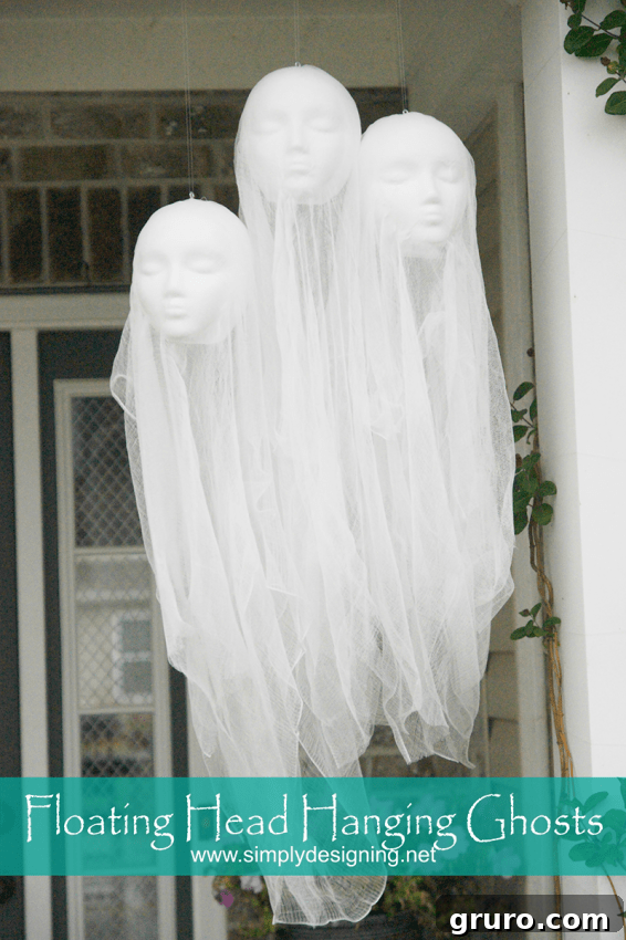 Several floating head ghosts made from mannequin heads and sheer white fabric, hanging outdoors.