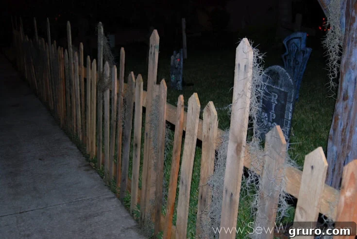A spooky Halloween wood pallet fence decorated with spiderwebs and pumpkins, creating a haunted perimeter.