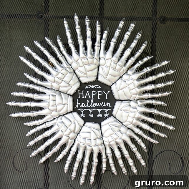 A Halloween wreath made with black mesh ribbon, orange accents, and skeleton hands, created from Dollar Store items.