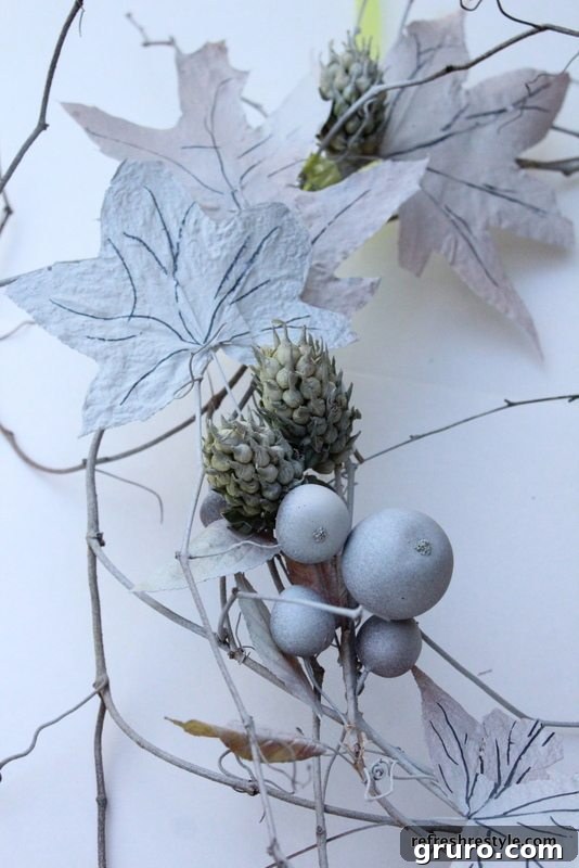 The wreath base adorned with dried leaves and artificial seed pods, ready for painting.