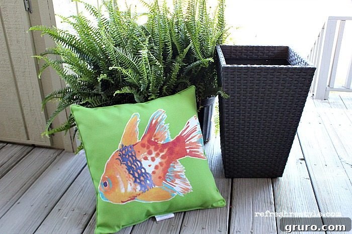 Outdoor seating area with new decorative pillows and vibrant green ferns