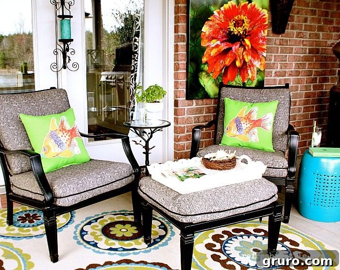 A cozy outdoor living area featuring a weather-resistant rug, decorative pillows, and outdoor prints, creating an inviting space.