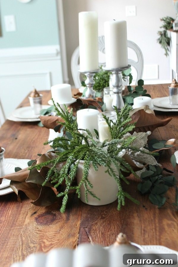 Dining room table centerpiece with natural greenery and elegant candles for Christmas