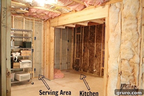 Before shot of a basement kitchen area needing renovation, showcasing an empty wall