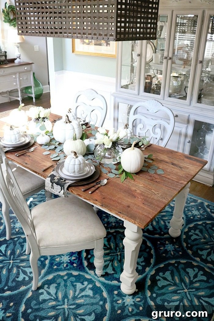 Farmhouse Autumn Gathering Table 8 Barn wood dining table with a neutral place setting, white pumpkins, and subtle hints of copper accents