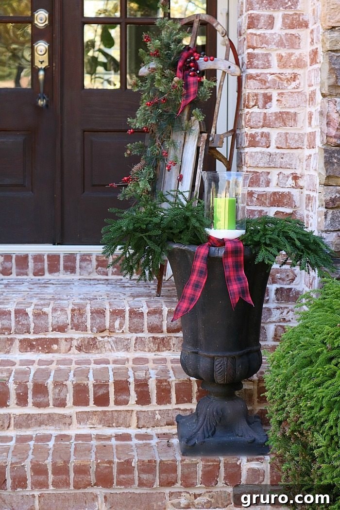 Rustic Christmas Porch - Plaid Ribbons and Old Sled Charm fill-an-urn-with-greenery-and-candles-and-plaid-ribbon-for-a-rustic-look-for-christmas