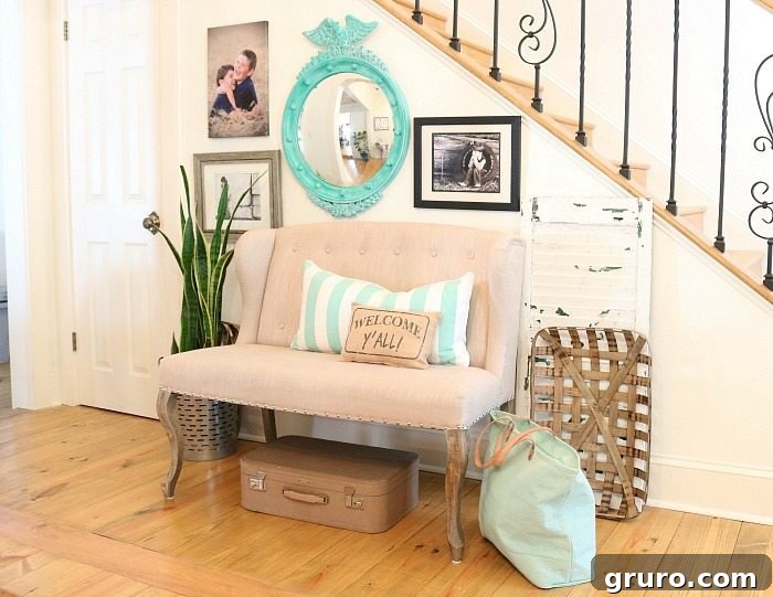 Family photos and other collected thrifty items arranged in the entry, with the turquoise federal convex mirror serving as a stylish focal point.