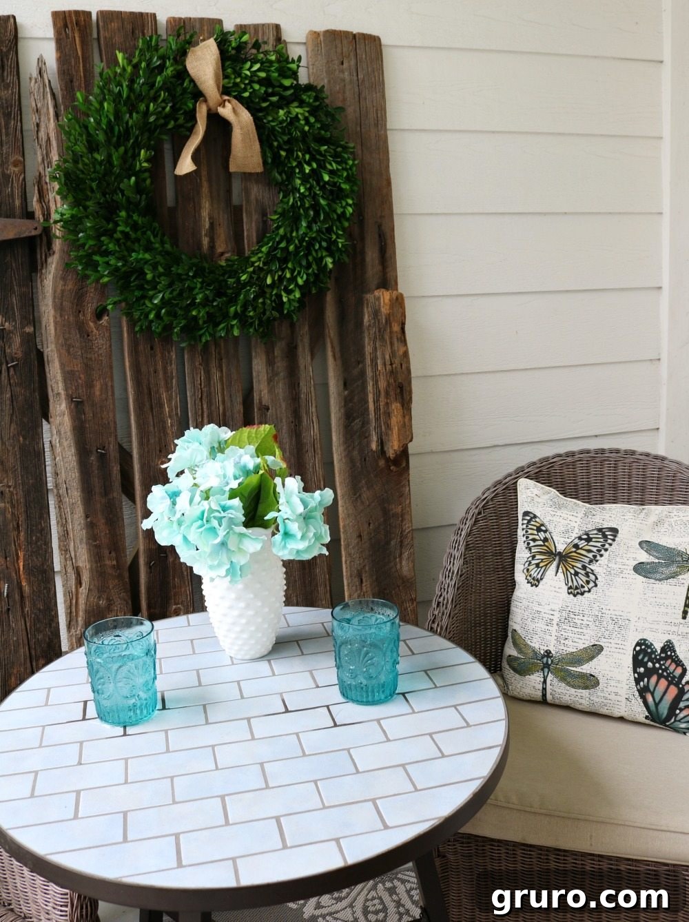 Barn door with a fresh boxwood wreath, enhancing the farmhouse style of the porch