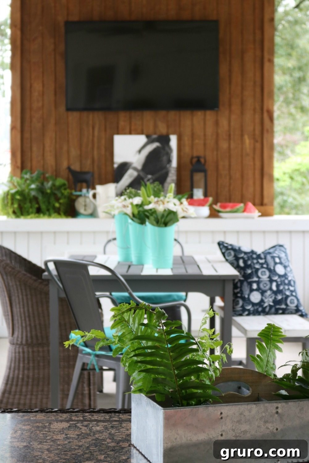 Galvanized metal planters with lush ferns decorating a farmhouse porch dining area