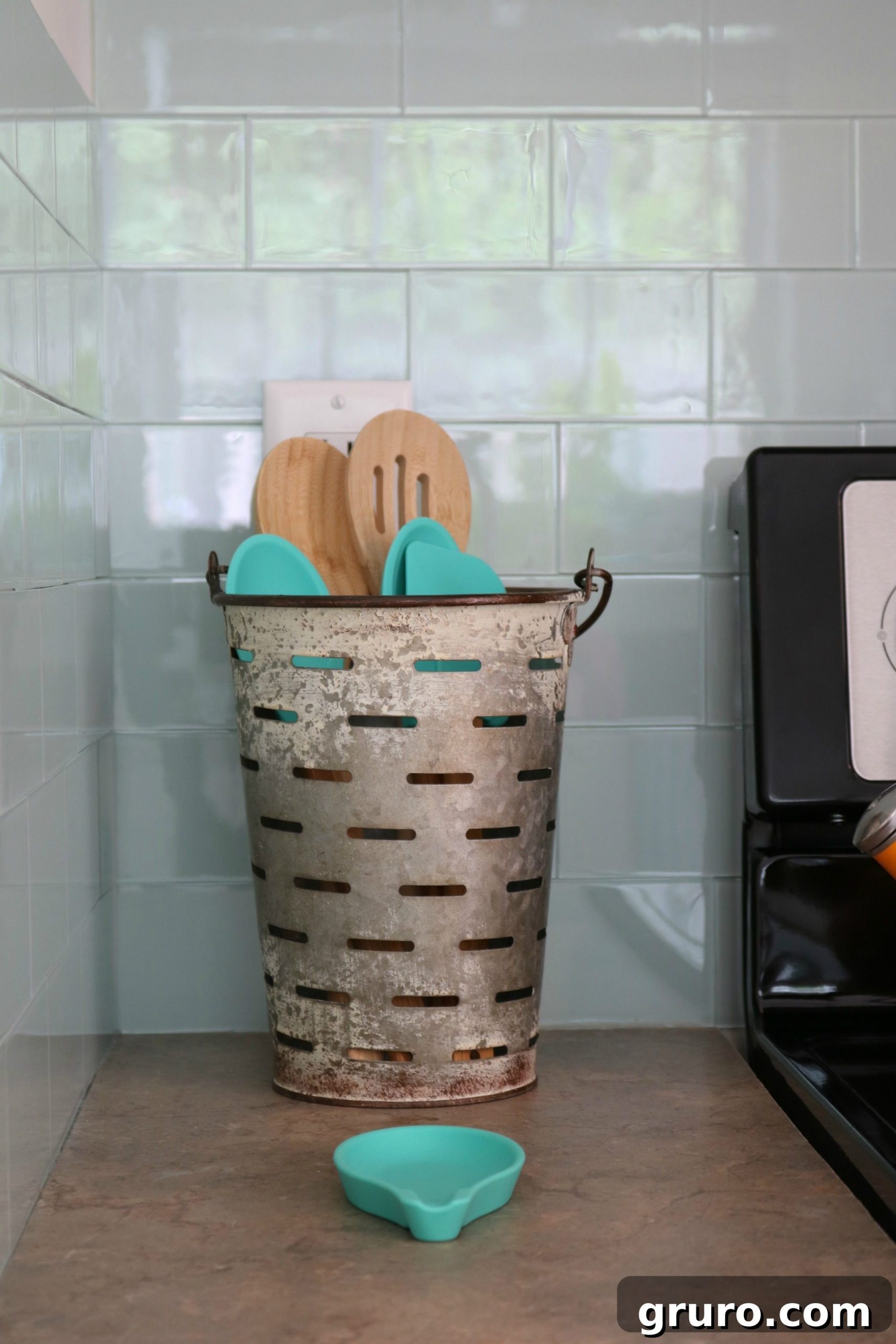 A charming faux olive bucket used as a stylish holder for spatulas and large spoons, embodying true farmhouse functionality and decor.