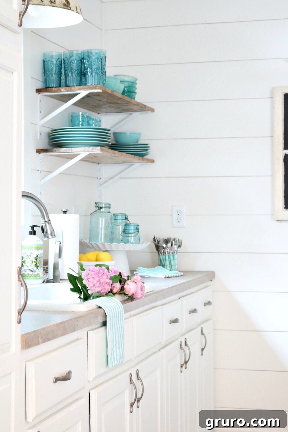 Clean white shiplap walls and minimalist open shelves define the classic farmhouse cottage look, offering a light and airy feel.