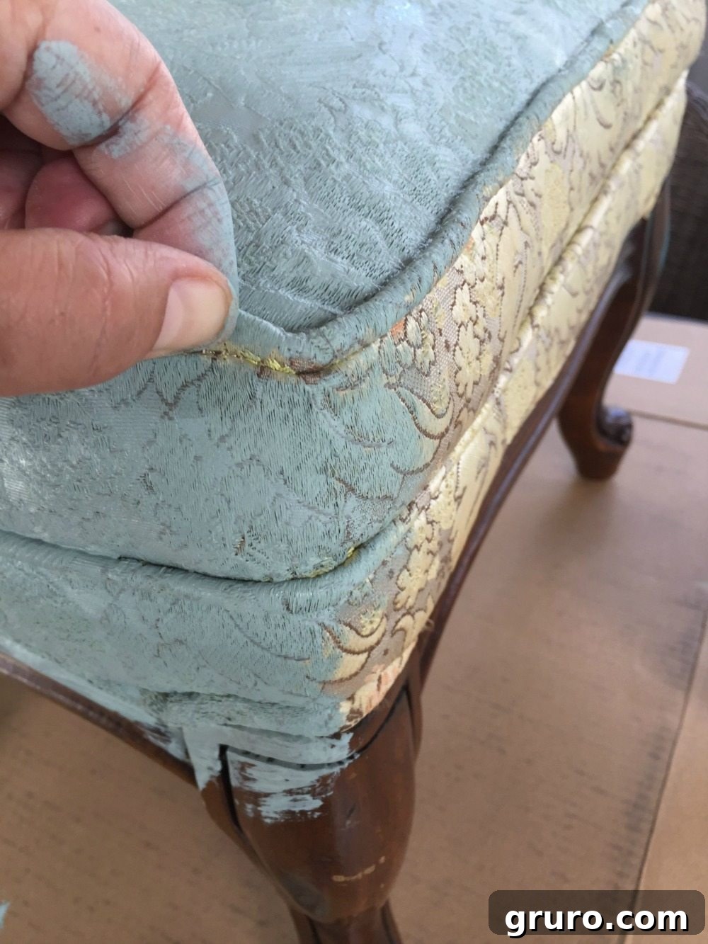 Detail shot of painting under the piping (welting) on a fabric ottoman for a clean finish