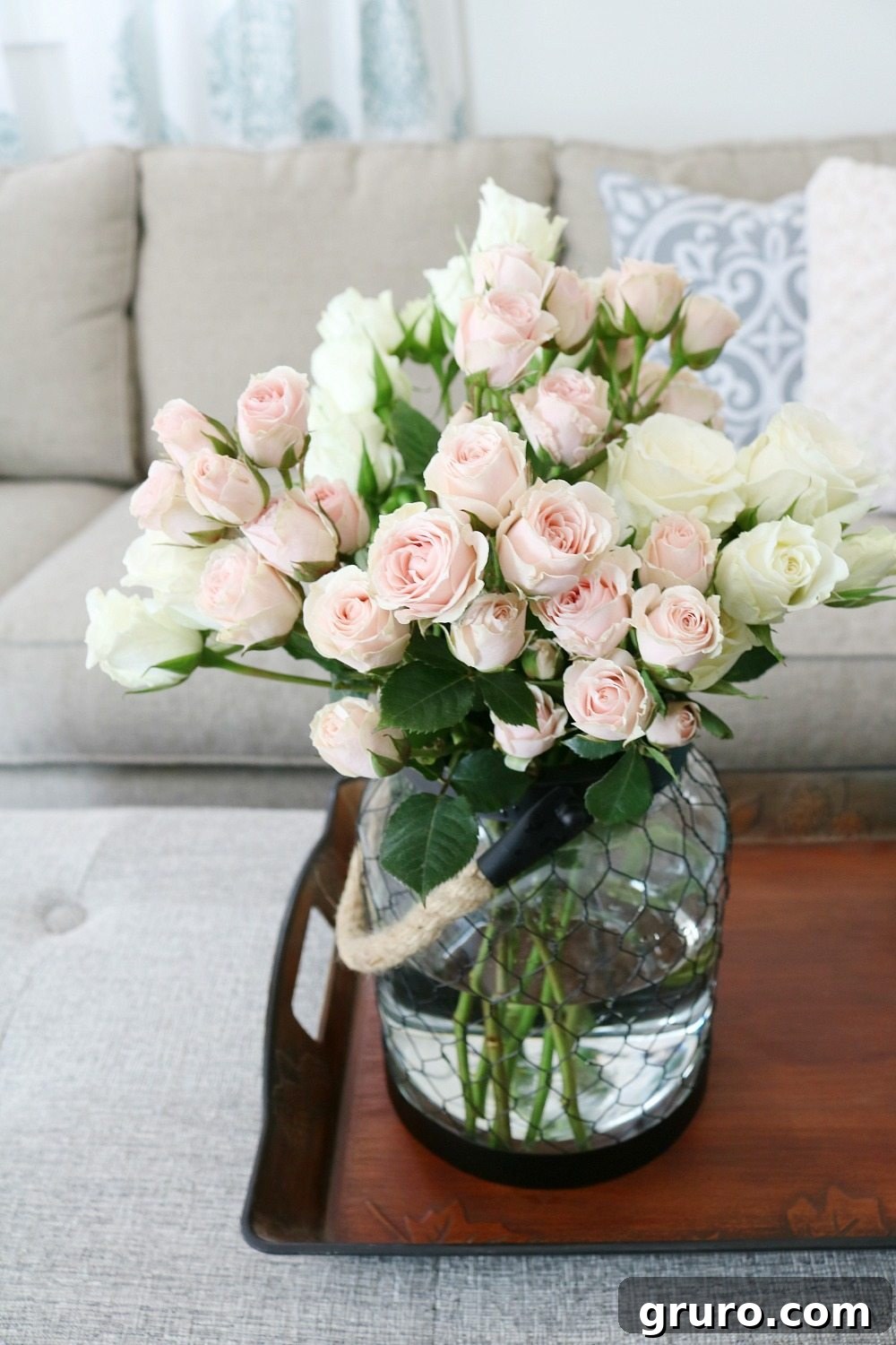 Fresh roses beautifully displayed in a farmhouse style rope handle candle holder on a storage bench